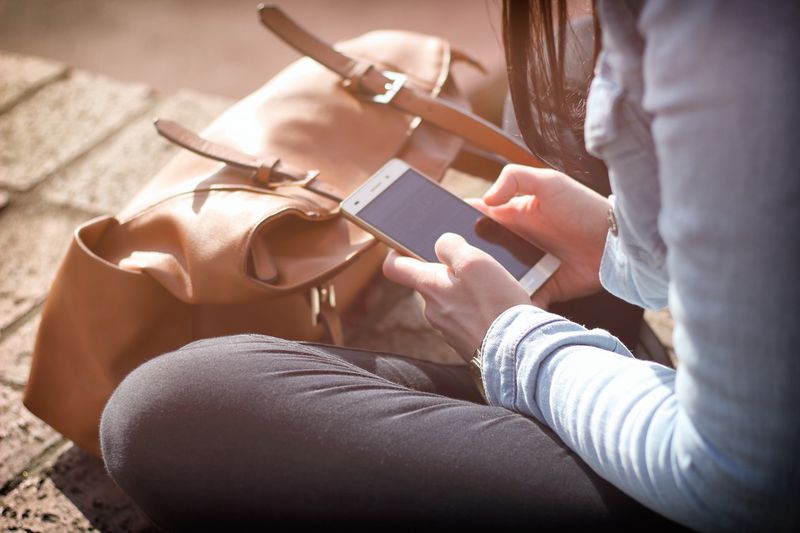 File:Person holding phone with bag.jpeg